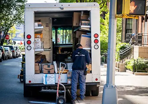 A USPS driver looking through packages in the back of his van.