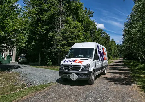 A FedEx delivery van on a small street.