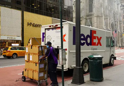A FedEx delivery driver delivering a lot of packages in the city.