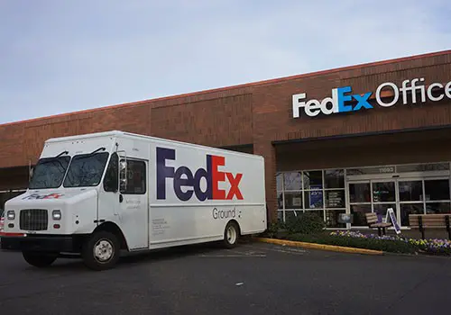 A FedEx truck parked outside a FedEx Office store.